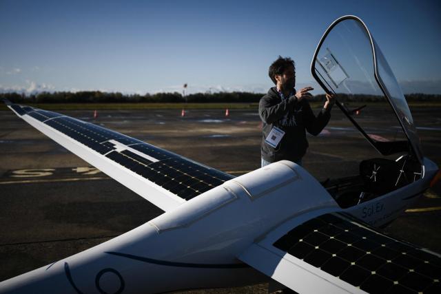 Engineer Jean-Baptiste Loiselet inspects his Sol.Ex solar glider, the world's first solar glider that combines wind and solar energy to fly autonomously without emitting CO2, at the General Aviation Days event at Pau-Pyrénées airport, south-western France, on November 26, 2025. The fifth edition of the professional gathering brings together pioneers of decarbonized light aviation to discuss new energy solutions including electricity, hydrogen and sustainable aviation fuels. (Photo by Philippe LOPEZ / AFP)