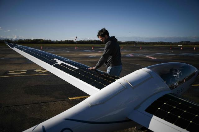 Engineer Jean-Baptiste Loiselet inspects his Sol.Ex solar glider, the world's first solar glider that combines wind and solar energy to fly autonomously without emitting CO2, at the General Aviation Days event at Pau-Pyrénées airport, south-western France, on November 26, 2025. The fifth edition of the professional gathering brings together pioneers of decarbonized light aviation to discuss new energy solutions including electricity, hydrogen and sustainable aviation fuels. (Photo by Philippe LOPEZ / AFP)