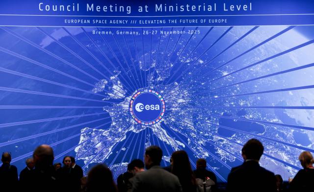 Delegates and medias stand in front of a screen displaying the ESA logo during the European Space Agency (ESA) ministerial meeting at the Congress Centrum in Bremen, northern Germany, on November 26, 2025. Ministers from the 23 member states of the European Space Agency (ESA) meet in the Hanseatic city for two days to discuss the strategic direction of European spaceflight. (Photo by FOCKE STRANGMANN / AFP)