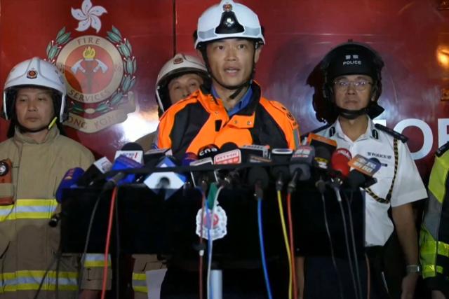 This frame grab from AFPTV video footage shows Chou Wing-yin of the Fire Services Department speaking to media amid ongoing operations to control a major fire at the Wang Fuk Court residential estate in Hong Kong's Tai Po district on November 26, 2025. At least 13 people have died as a result of a raging fire that tore through several high-rise blocks in a Hong Kong residential estate on November 26, a government official said. (Photo by AFPTV / AFP)