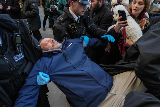 Police begin to remove protesters have gathered to take part in a demonstration in support of "Defend Our Juries" and their campaign against the ban on Palestine Action, outside the Royal Courts of Justice, Britain's High Court, in central London on November 26, 2025. The co-founder of activist group Palestine Action will on November 26 challenge a UK government ban under anti-terror laws that has led to mass arrests, sparking free speech and civil liberties concerns. (Photo by CARLOS JASSO / AFP)