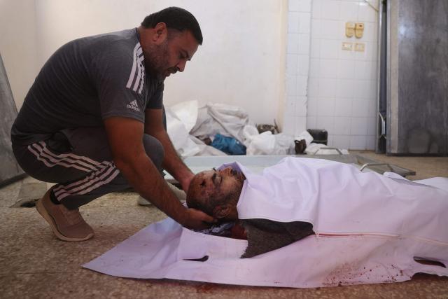 EDITORS NOTE: Graphic content / A Palestinian man mourns over the body of 51-year-old Ashraf Khadora killed in an Israeli strike at Al-Aqsa hospital in Deir al-Balah in the central Gaza Strip on November 26, 2025. The Gaza Strip has been largely reduced to rubble after two years of fighting, sparked by Hamas's attack on Israel on October 7, 2023, which resulted in the deaths of 1,221 people. Israel's retaliatory assault on Gaza has killed at least 69,733 people, according to figures from the health ministry that the UN considers reliable. (Photo by BASHAR TALEB / AFP)