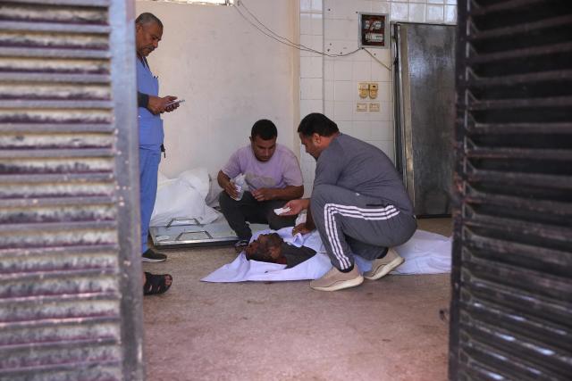 EDITORS NOTE: Graphic content / Palestinians mourn over the body of 51-year-old Ashraf Khadora killed in an Israeli strike at Al-Aqsa hospital in Deir al-Balah in the central Gaza Strip on November 26, 2025. The Gaza Strip has been largely reduced to rubble after two years of fighting, sparked by Hamas's attack on Israel on October 7, 2023, which resulted in the deaths of 1,221 people. Israel's retaliatory assault on Gaza has killed at least 69,733 people, according to figures from the health ministry that the UN considers reliable. (Photo by BASHAR TALEB / AFP)