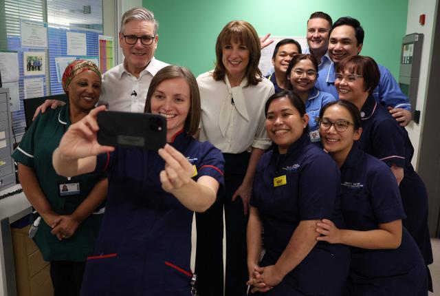 Britain's Chancellor of the Exchequer Rachel Reeves (C) and Britain's Prime Minister Keir Starmer (2L) pose for a selfie photograph with nursing staff during a visit to University College London Hospital in London, on November 26, 2025. (Photo by Adrian DENNIS / POOL / AFP)