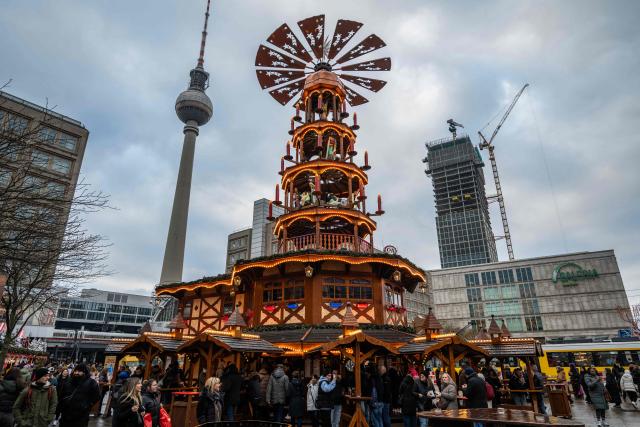 Visitors crowd a giant Christmas Pyramid at the Alexanderplatz Christmas market in Berlin on November 26, 2025, ahead of the holidays season. (Photo by John MACDOUGALL / AFP)
