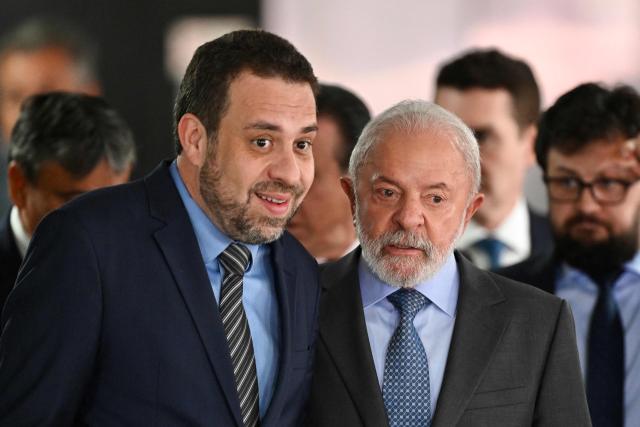Brazil's President Luiz Inacio Lula da Silva (R) and his Chief Minister of the General Secretariat of the Presidency, Guilherme Boulos, talk as they arrive for the signing ceremony of the new Income Tax Law at the Planalto Palace in Brasilia. on November 26, 2025. (Photo by Evaristo Sa / AFP)