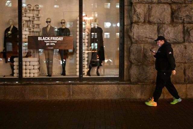 A pdestrian walks past a Mango clothing shop promoting Black Friday sales during a power outage in Kyiv on November 26, 2025, amid the Russian invasion of Ukraine.  (Photo by Sergei GAPON / AFP)