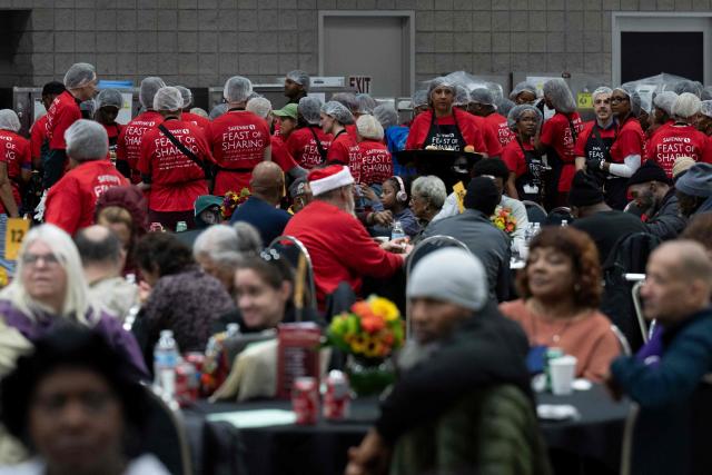 Volunteers serve food to local residents in need during the 26th annual Safeway Feast of Sharing at the Washington Convention Center in Washington, DC on November 26, 2025. The annual event provides Thanksgiving meals for thousands of people in need. (Photo by Brendan Smialowski / AFP)