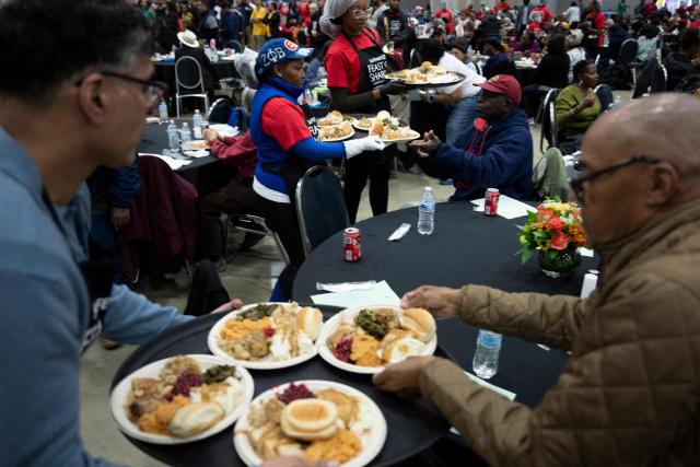 Volunteers serve food to local residents in need during the 26th annual Safeway Feast of Sharing at the Washington Convention Center in Washington, DC on November 26, 2025. The annual event provides Thanksgiving meals for thousands of people in need. (Photo by Brendan Smialowski / AFP)