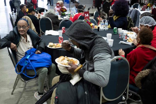 People eat a holiday meal during the 26th annual Safeway Feast of Sharing at the Washington Convention Center in Washington, DC on November 26, 2025. The annual event provides Thanksgiving meals for thousands of people in need. (Photo by Brendan Smialowski / AFP)