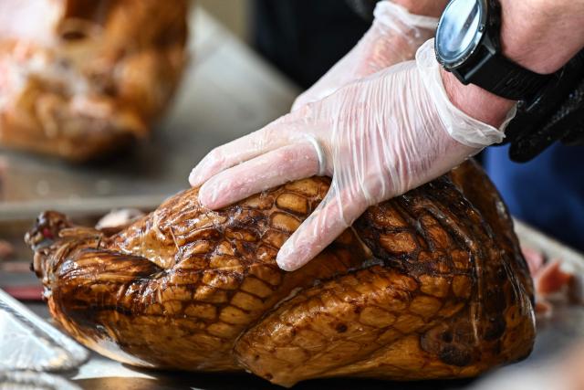 A volunteer at St. Paul's United Methodist Church carves a turkey in preparation for the Thanksgiving food distribution, when they will deliver 13,500 meals to people in need, as part of "Operation Turkey" in Houston, Texas on November 26, 2025. (Photo by RONALDO SCHEMIDT / AFP)