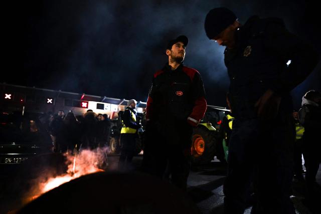 Protesters stand beside a fire during a demonstration of French agricultural unions FNSEA and Jeunes Agriculteurs of the Seine-Maritime and Eure departments to protest the EU-Mercosur agreements and taxes affected their sector, on the Tancarville Bridge, in Tancarville, on November 26, 2025. (Photo by Lou BENOIST / AFP)