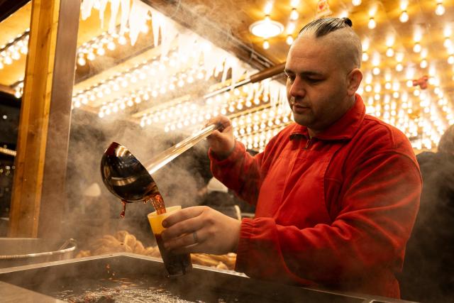 A vendor pours traditional hot wine into a cup before selling it to a customer at the Christmas market in Strasbourg, eastern France, on November 26, 2025. (Photo by ROMEO BOETZLE / AFP)