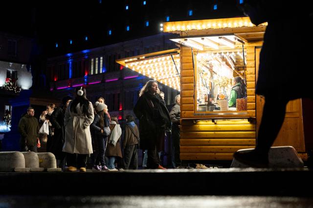 Visitors walk past a food stand in an alley of the Christmas market in Strasbourg, eastern France, on November 26, 2025. Strasbourg's Christmas market, a major tourist attraction in Alsace, opened its 300 chalets on November 26, 2025, in the center of a city under heightened security amid a persistent terrorist threat. (Photo by ROMEO BOETZLE / AFP)