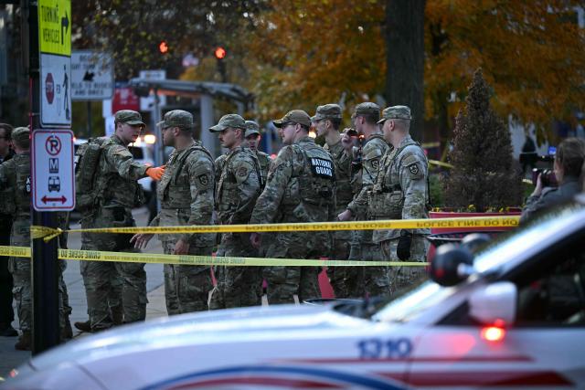 National Guard soldiers stand behind the crime scene tape at a corner in downtown Washington, DC, on November 26, 2025. Two National Guard soldiers were shot a few blocks from the White House, according to law enforcement. (Photo by Drew ANGERER / AFP)