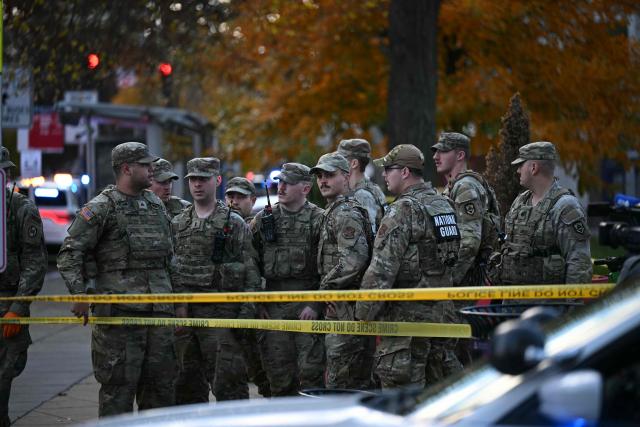 National Guard soldiers stand behind the crime scene tape at a corner in downtown Washington, DC, on November 26, 2025. Two National Guard soldiers were shot a few blocks from the White House, according to law enforcement. (Photo by Drew ANGERER / AFP)