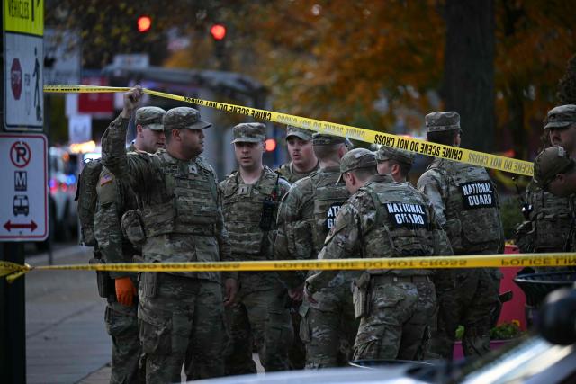 National Guard soldiers stand behind the crime scene tape at a corner in downtown Washington, DC, on November 26, 2025. Two National Guard soldiers were shot a few blocks from the White House, according to law enforcement. (Photo by Drew ANGERER / AFP)