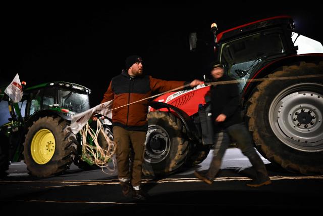 Protesters prepare weighted water containers to hang up during a demonstration of French agricultural unions FNSEA and Jeunes Agriculteurs of the Seine-Maritime and Eure departments to protest the EU-Mercosur agreements and taxes affected their sector, on the Tancarville Bridge, in Tancarville, on November 26, 2025. (Photo by Lou BENOIST / AFP)