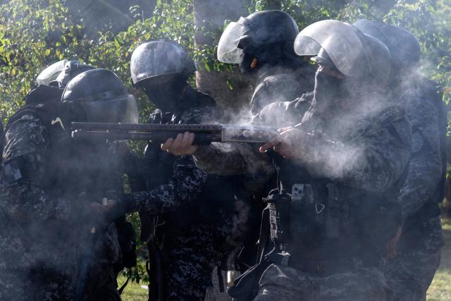 Military Police officers fire rubber bullets during clashes as fans of Brazil's Flamengo accompany a bus carrying the team on its way to Galeao International Airport in Rio de Janeiro, Brazil, on November 26, 2025. Flamengo team flew to Lima Wednesday to face Palmeiras in the Libertadores Cup final match, which will take place on November 29. (Photo by Pablo PORCIUNCULA / AFP)