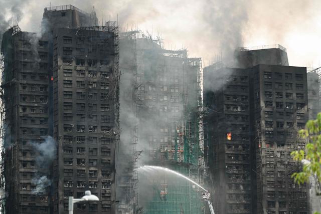Firefighters spray water on flames as a major fire burns through several apartment blocks at the Wang Fuk Court residential estate in Hong Kong's Tai Po district on November 27, 2025. The death toll from a high-rise fire in Hong Kong has risen to at least 44, officials said on November 27 as the blaze still smoldered and police said three suspects were arrested. (Photo by Peter PARKS / AFP)