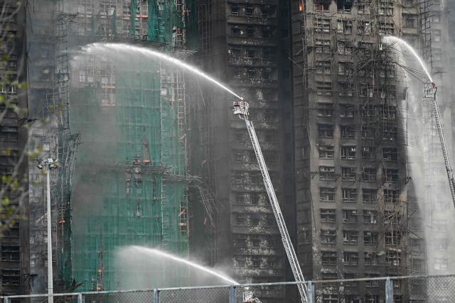Firefighters spray water on flames as a major fire burns through several apartment blocks at the Wang Fuk Court residential estate in Hong Kong's Tai Po district on November 27, 2025. The death toll from a high-rise fire in Hong Kong has risen to at least 44, officials said on November 27 as the blaze still smoldered and police said three suspects were arrested. (Photo by Peter PARKS / AFP)