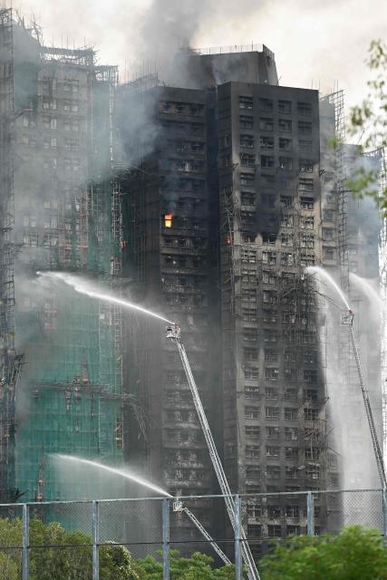 Firefighters spray water on flames as a major fire burns through several apartment blocks at the Wang Fuk Court residential estate in Hong Kong's Tai Po district on November 27, 2025. The death toll from a high-rise fire in Hong Kong has risen to at least 44, officials said on November 27 as the blaze still smoldered and police said three suspects were arrested. (Photo by Peter PARKS / AFP)