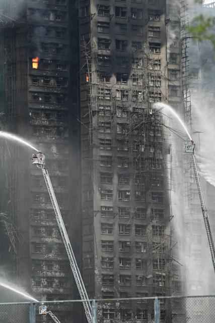 Firefighters spray water on flames as a major fire burns through several apartment blocks at the Wang Fuk Court residential estate in Hong Kong's Tai Po district on November 27, 2025. The death toll from a high-rise fire in Hong Kong has risen to at least 44, officials said on November 27 as the blaze still smoldered and police said three suspects were arrested. (Photo by Peter PARKS / AFP)