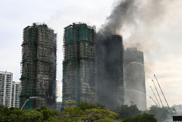 Firefighters spray water on flames as a major fire burns through several apartment blocks at the Wang Fuk Court residential estate in Hong Kong's Tai Po district on November 27, 2025. The death toll from a high-rise fire in Hong Kong has risen to at least 44, officials said on November 27 as the blaze still smoldered and police said three suspects were arrested. (Photo by Peter PARKS / AFP)