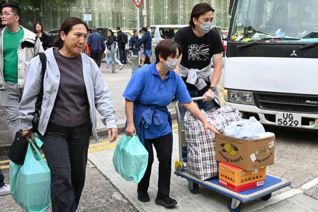 Local residents bring essential items to donate at the Fung Leung Kit Secondary School, one of the community centres allocated for affected residents after a major fire swept through several apartment blocks at the Wang Fuk Court residential estate in Hong Kong's Tai Po district on November 27, 2025. Firefighters were still dousing a devastating fire on November 27 which ripped through a Hong Kong high-rise complex, killing at least 44 people and leaving hundreds missing according to authorities. (Photo by Peter PARKS / AFP)