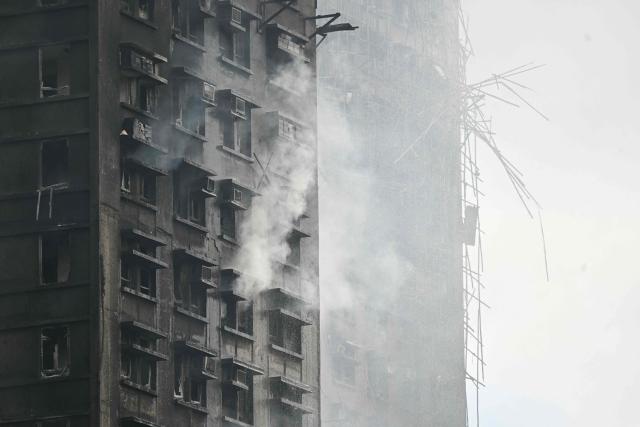 An apartment still smoulders after a major fire swept through several apartment blocks at the Wang Fuk Court residential estate in Hong Kong's Tai Po district on November 27, 2025. Firefighters were still dousing a devastating fire on November 27 which ripped through a Hong Kong high-rise complex, killing at least 44 people and leaving hundreds missing according to authorities. (Photo by Peter PARKS / AFP)