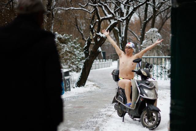 A winter swimmer poses for pictures on a scooter at Beiling Park during the first heavy snowfall of the season in Shenyang, northeast China's Liaoning province on November 27, 2025. (Photo by AFP) / China OUT