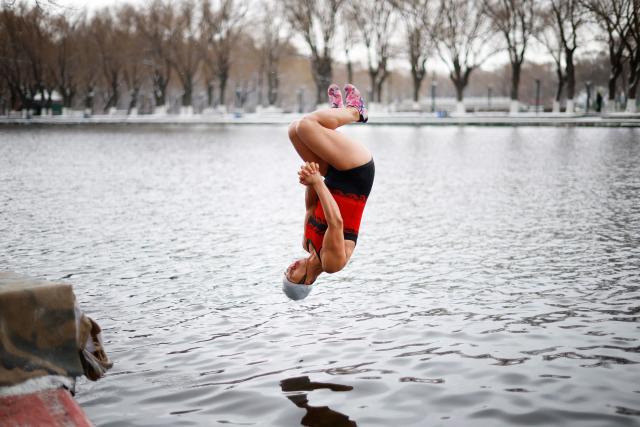 A winter swimmer dives into a lake at Beiling Park during the first heavy snowfall of the season in Shenyang, northeast China's Liaoning province on November 27, 2025. (Photo by AFP) / China OUT