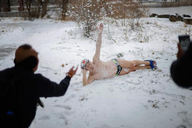 A winter swimmer poses for pictures as he lies on the snow-covered ground at Beiling Park during the first heavy snowfall of the season in Shenyang, northeast China's Liaoning province on November 27, 2025. (Photo by AFP) / China OUT