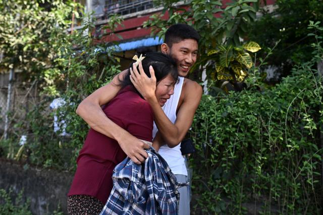 TOPSHOT - A relative hugs a released inmate (R) outside Insein prison in Yangon on November 27, 2025. Prisoners were released from Insein prison in Yangon on November 27 a day after Myanmar's junta dropped the sentences of more than 3,000 people convicted under legislation that monitors say was wielded to crush post-coup dissent, encouraging them to vote in upcoming polls. (Photo by Sai Aung MAIN / AFP)