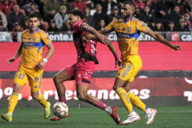 Tijuana's Moroccan forward #21 Mourad Daoudi (C) fights for the ball with Tigres' Brazilian defender #02 Joaquim Pereira (R) during first leg of the Liga MX Clausura quarterfinal match between Tijuana and Tigres at Caliente Stadium in Tijuana, Baja California State, Mexico, on November 26, 2025. (Photo by Guillermo Arias / AFP)