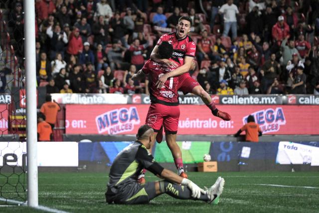 Tijuana's Moroccan forward #21 Mourad Daoudi (C) and Tijuana's Mexican defender #03 Rafael Fernandez (top) celebrate their team's first goal as Tigres' Argentine goalkeeper #01 Nahuel Guzman (L) looks on during first leg of the Liga MX Clausura quarterfinal match between Tijuana and Tigres at Caliente Stadium in Tijuana, Baja California State, Mexico, on November 26, 2025. (Photo by Guillermo Arias / AFP)