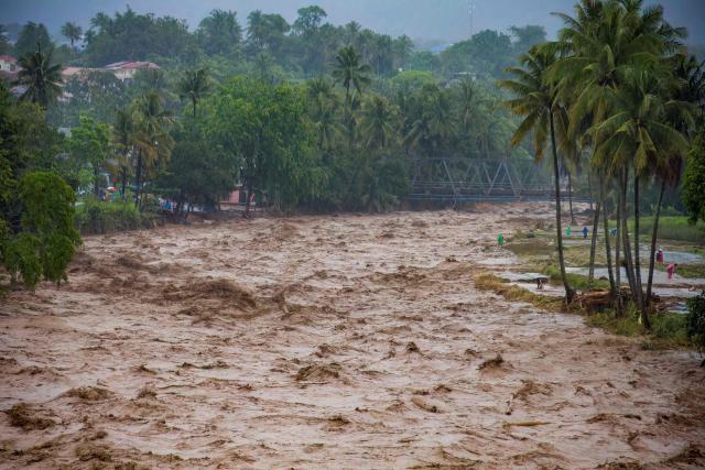 People stay on the river banks during flooding in Padang, West Sumatra province on November 27, 2025. (Photo by REZAN SOLEH / AFP)