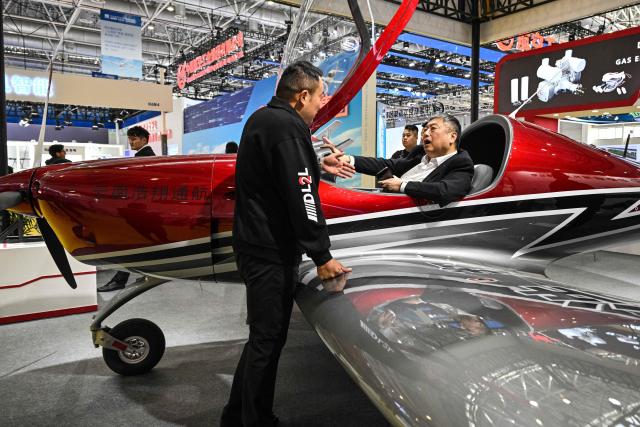 A man sits in an aircraft in the booth of Mile Haoxiang Technology Co., Ltd. during the Aero Asia 2025 in Zhuhai, in southern China's Guangdong province on November 27, 2025. Aero Asia 2025 is an international aviation and aerospace exhibition that runs between November 27 and 30. (Photo by Hector RETAMAL / AFP)