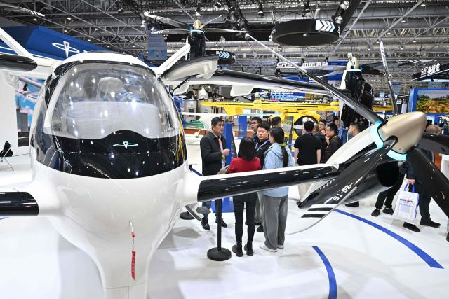 Visitors are seen next to a Zerog eVTOL model ZG-T6 in the Zerog booth during the Aero Asia 2025 in Zhuhai, in southern China's Guangdong province on November 27, 2025. Aero Asia 2025 is an international aviation and aerospace exhibition that runs between November 27 and 30. (Photo by Hector RETAMAL / AFP)