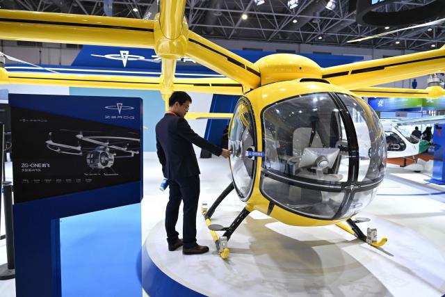 A visitor is seen next to a Zerog eVTOL model ZG-ONE in the Zerog booth during the Aero Asia 2025 in Zhuhai, in southern China's Guangdong province on November 27, 2025. Aero Asia 2025 is an international aviation and aerospace exhibition that runs between November 27 and 30. (Photo by Hector RETAMAL / AFP)