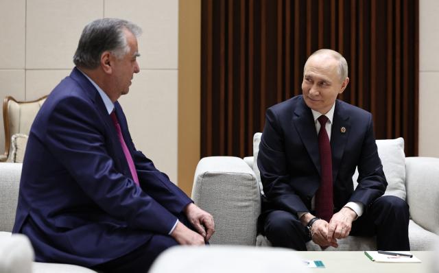 In this pool photograph distributed by the Russian state agency Sputnik, Russia's President Vladimir Putin meets with Tajikistan's President Emomali Rakhmon after a meeting of the Collective Security Treaty Organisation (CSTO) Heads of State Council in Bishkek on November 27, 2025. (Photo by Alexander KAZAKOV / POOL / AFP)