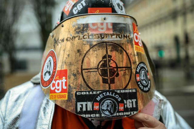 An employee of ArcelorMittal wears a welding mask with stickers of the CGT union during an action called by French trade union General Confederation of Labour (CGT) on the Esplanade des Invalides to support the LFI draft bill examined today by MPs to nationalize French operations of the steelmaking giant which is facing severe difficulties, near the French national Assembly in Paris on November 27, 2025. (Photo by Alain JOCARD / AFP)