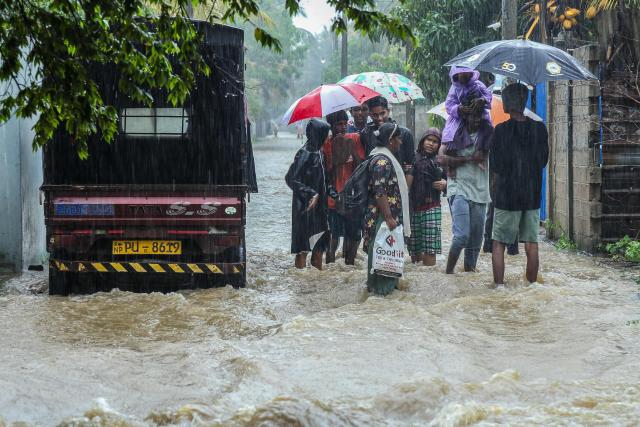 Residents wade through a flooded street during heavy rainfall in Puttalam on November 27, 2025. Floods and landslides triggered by heavy rain killed at least 40 people and injured 10 across Sri Lanka this week, with 21 others missing, authorities said November 27. (Photo by AFP)
