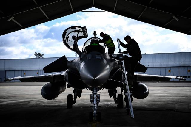 A French pilot (R) climbs into a Rafale fighter jet ahead of a flight at a military air base during the Garuda 2025 French-Indian military cooperation exercise in Mont-de-Marsan, southwestern France, on November 26, 2025. (Photo by Christophe ARCHAMBAULT / AFP)