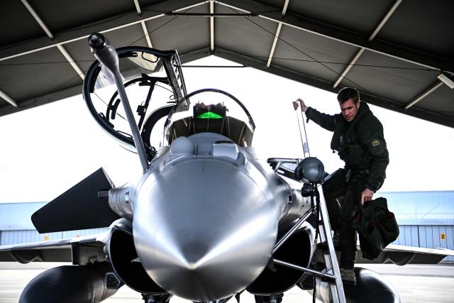 A French pilot climbs into a Rafale fighter jet ahead of a flight at a military air base during the Garuda 2025 French-Indian military cooperation exercise in Mont-de-Marsan, southwestern France, on November 26, 2025. (Photo by Christophe ARCHAMBAULT / AFP)