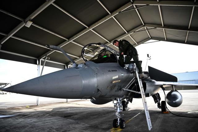 A French pilot climbs into a Rafale fighter jet ahead of a flight at a military air base during the Garuda 2025 French-Indian military cooperation exercise in Mont-de-Marsan, southwestern France, on November 26, 2025. (Photo by Christophe ARCHAMBAULT / AFP)