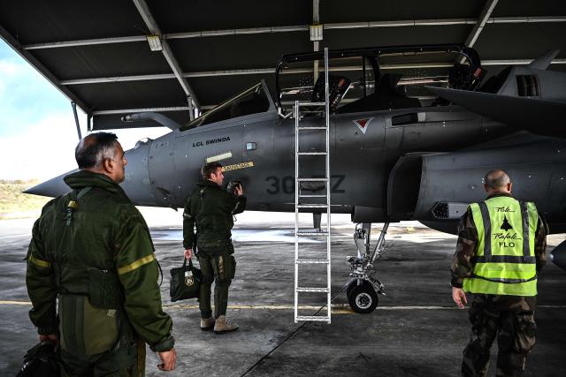 Pilots perform pre-flight checks on a Rafale fighter jet ahead of a flight at a military air base during the Garuda 2025 French-Indian military cooperation exercise in Mont-de-Marsan, southwestern France, on November 26, 2025. (Photo by Christophe ARCHAMBAULT / AFP)