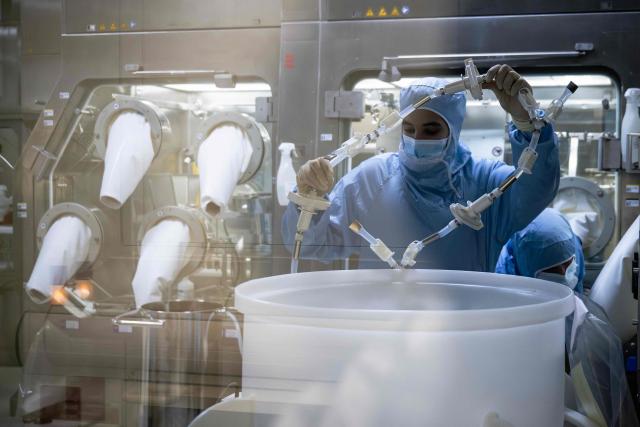 An employee wearing personal protective equipment (PPE) works on a production line during a press tour of the new biotechnology production facility at the industrial site of French pharmaceutical group Sanofi in Le Trait, southwestern France, on November 27, 2025. (Photo by LOU BENOIST / AFP)