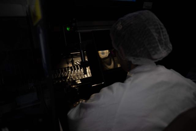 An employee works on tubes for medication syringes on a production line during a press tour of the new biotechnology production facility at the industrial site of French pharmaceutical group Sanofi in Le Trait, southwestern France, on November 27, 2025. (Photo by LOU BENOIST / AFP)
