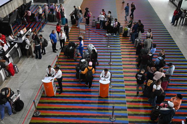 Passengers queue at counters at Simon Bolivar International Airport in Maiquetia, La Guaira State, Venezuela, on November 27, 2025. Venezuela's decision to ban foreign airlines that stopped flying to the Caribbean country over concerns about US military activity was branded "disproportionate" on Thursday as thousands of passengers scrambled to save their travel plans. (Photo by Federico PARRA / AFP)